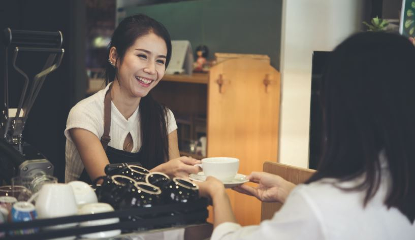 Female barista handing a customer their beverage